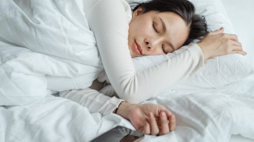 Dame sover i seng med dyne og pude